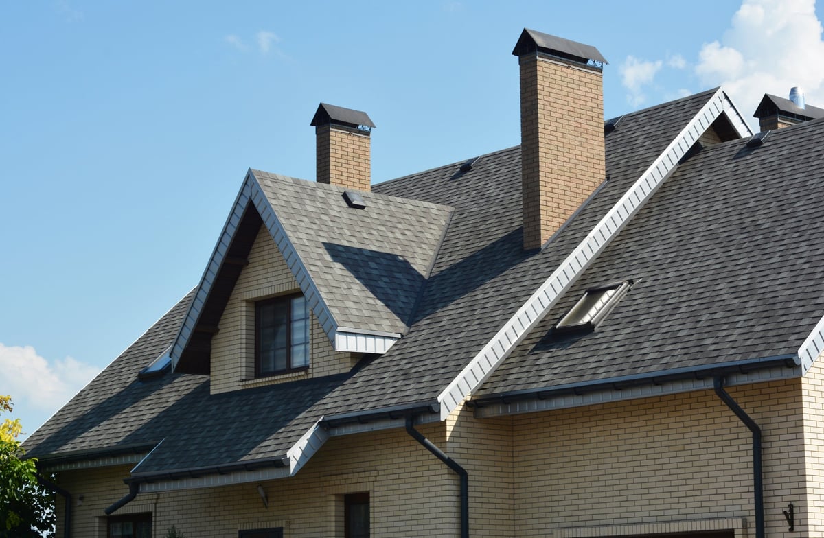 Typical suburban house with standard asphalt shingle roof, dormer window, rain gutters, and soffits